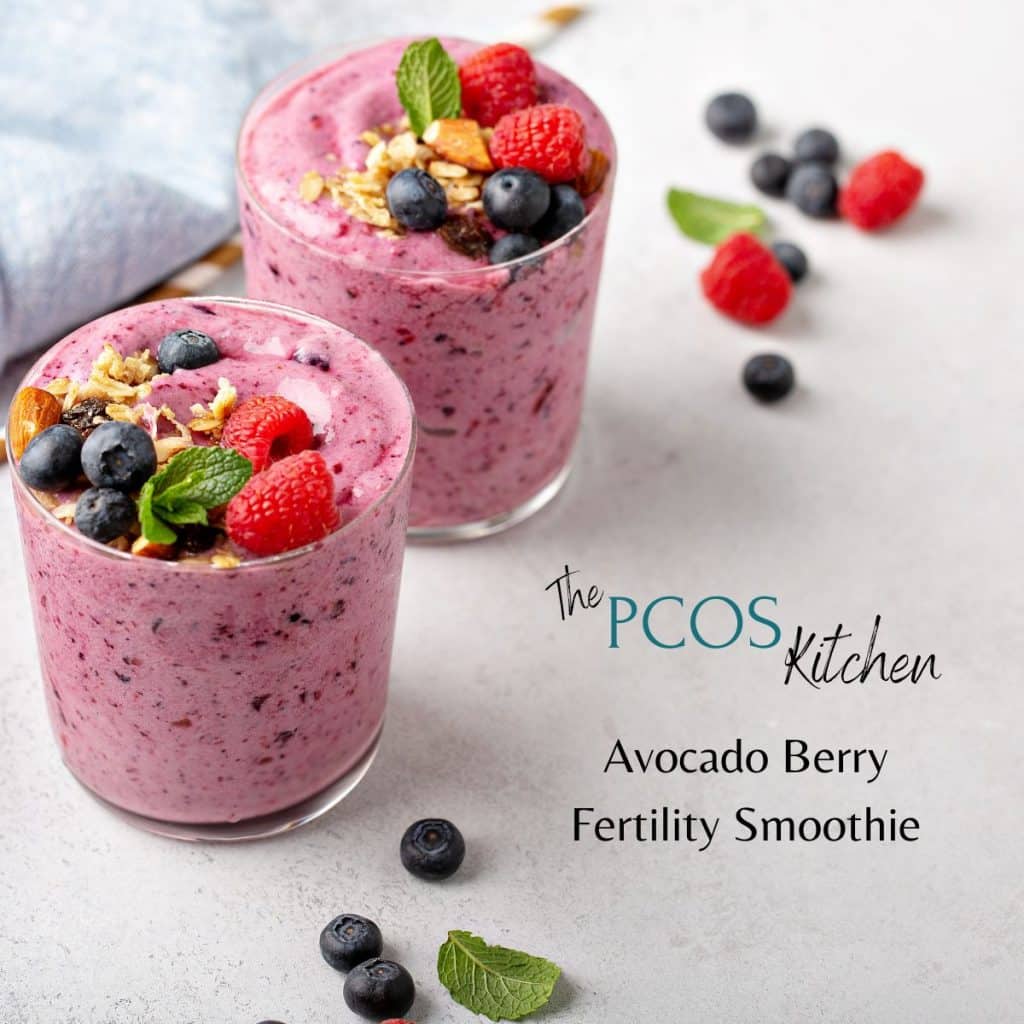 PCOS Smoothies. Picture of two glasses of the Avocado Berry Fertility smoothie by The PCOS Kitchen. The pink/purple colored smoothies are garnished with blueberries, raspberries, mint and almonds.