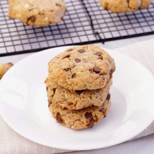 picture of a stack PCOS-friendly oatmeal Chocolate chip breakfast bars on white plate with a banana and glass of milk in background.